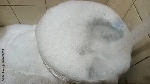 Pouring Water into Pail Creating Thick Soap Bubbles
