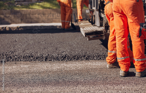 Construction worker working on a new asphalt layer on a public street.