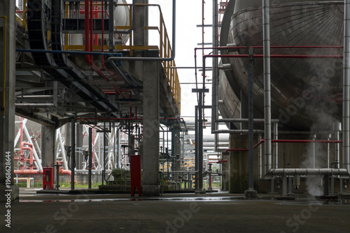 Large industrial building with pipes and a red fire extinguisher. The building is empty and the atmosphere is industrial