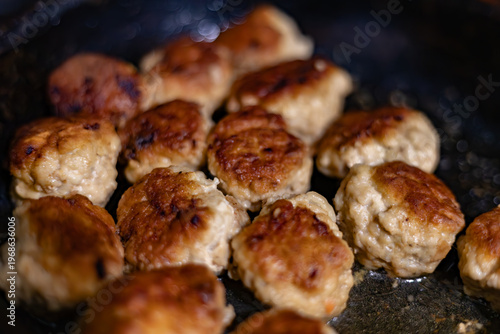Golden brown homemade meatballs frying in a pan