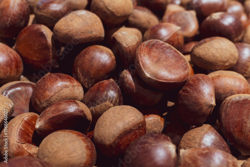 Rich, glossy chestnuts piled close together. Smooth, brown shells show natural texture. Ideal for autumn, food, or harvest-themed projects. Perfect for cookbooks, seasonal ads