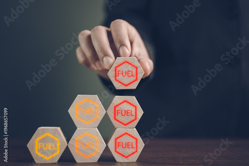 Fotografía Hand stacking wooden hexagons with fuel labels representing energy resource mana