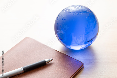 手帳とボールペンとガラス製の地球儀