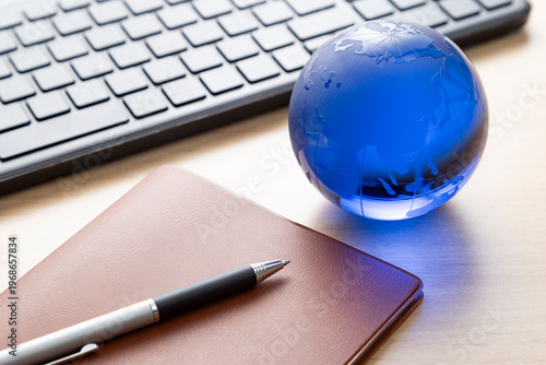 パソコンと手帳とガラス製の地球儀