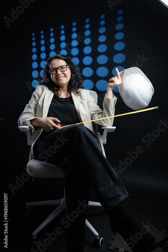 Woman engineer smiling holding hard hat and measuring tape