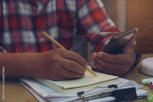 Planner or organizer writing daily appointment On Calendar book and using smartphone. Asian man hand plan timetable meeting agenda, and note schedule business in diary. Planner concept.