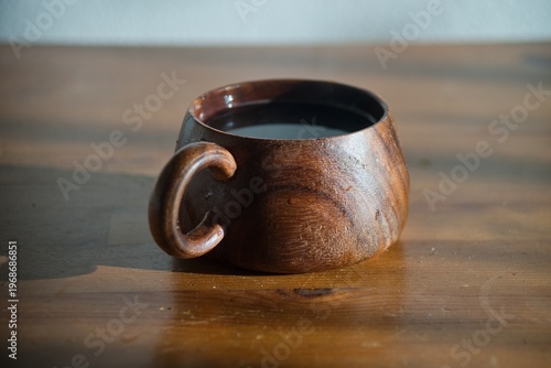 Handcrafted Wooden Coffee Mug with Dark Coffee on Wooden Table