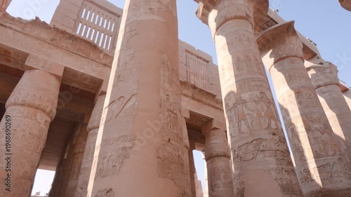 Low angle view of the massive stone columns with intricate hieroglyphics in the Great Hypostyle Hall at Karnak Temple in Luxor, Egypt.