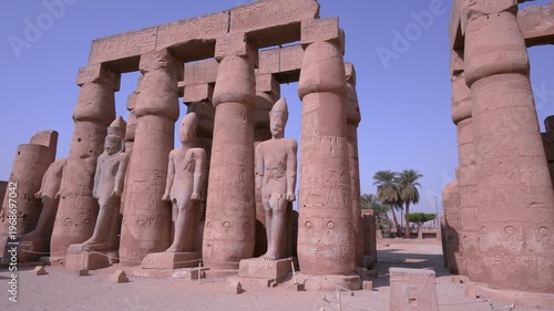 A view of ancient stone statues and towering columns with hieroglyphics at the historic Luxor Temple in Luxor, Egypt.