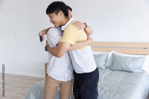 Keys and headphones are resting on bed near wooden headboard in tidy bedroom with light floor