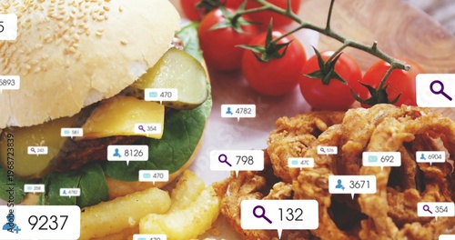 Showing sesame burger with cheddar, pickles on wood board, fries, onion rings, tomatoes, UI badges