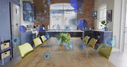 Anchoring wooden table holding potted plant in kitchen with chartreuse chairs and blue overlays
