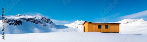 Solitary golden cabin, a vibrant contrast, nestled in a pristine, snow-covered alpine valley with majestic jagged peaks under a brilliant blue sky, depicting modern refuge. Alpine,