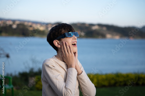 Teenage boy observing solar eclipse with protective glasses outdoors

