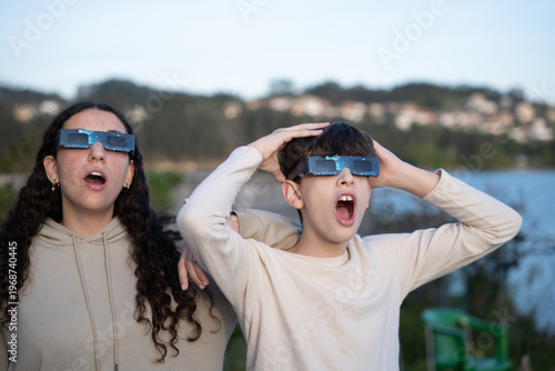 Teenagers watching solar eclipse with protective glasses outdoors