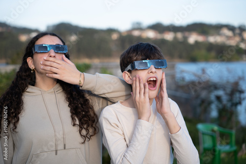 Teenagers watching solar eclipse with protective glasses outdoors