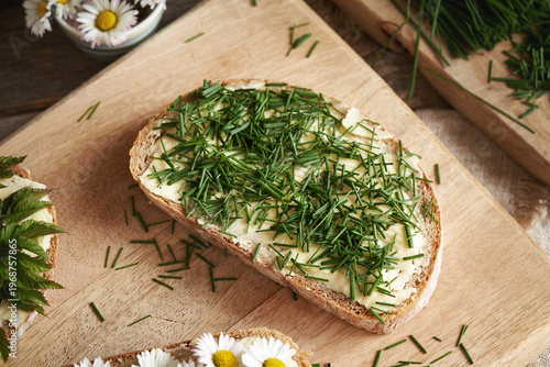 Spring wild edible plants - crow garlic, ground elder, common daisy on slices of bread