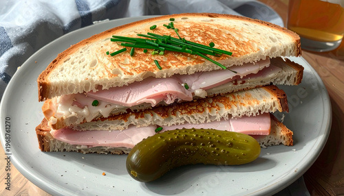 Slice of toasted bread with ham and a whole gherkin pickle garnished with chives