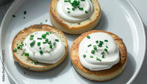 Toasted bread rounds topped with cream cheese and fresh chives on a white plate