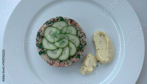 Meat tartare topped with fresh cucumber slices served with herb mashed potatoes on white plate
