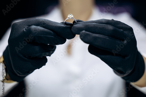 Professional jeweler's gloved hands carefully examining a diamond engagement ring, ensuring quality and precision for a client