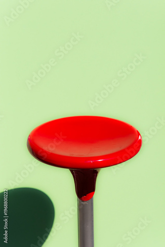 Dettaglio di uno sgabello rosso davanti a una parete verde