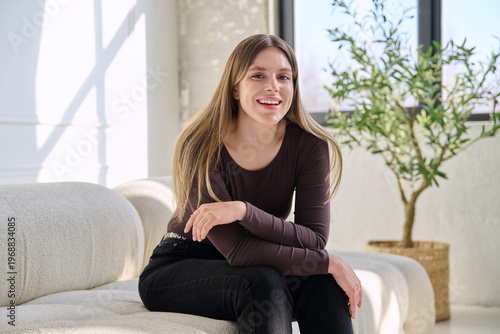 Portrait of relaxed beautiful young woman sitting at home on sofa