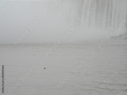 Misty waterfall edge above calm winter river