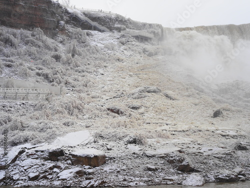 Icy riverbank with rocks and rushing winter water