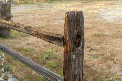 A old wooden rail fence with texture and a background of dry grass