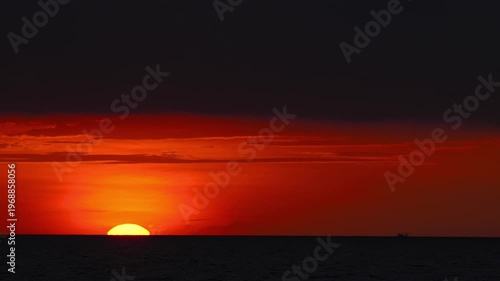 Stunning view of the glowing sun sinking into the sea at sunset. Tranquil and cinematic ocean horizon scene.
