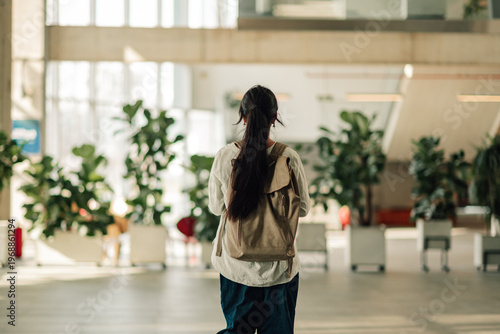 Young woman student walking in university building, carrying backpack, ready for education and future career path