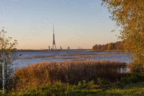 Tall tower rises above tranquil waters at sunset, capturing the beauty of nature and city life in harmony during golden hour