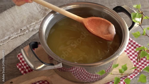 Preparation of homemade dandelion syrup or honey - stirring sugar in water in which fresh dandelion blossoms have been macerated