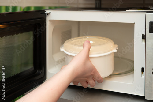 Картината върху платно Putting food container into microwave oven