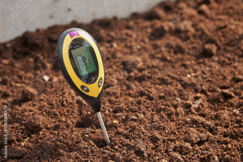 Soil temperature before planting crops. An electronic soil thermometer shows a temperature of 18 degrees Celsius at depth.