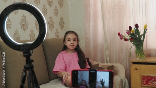 A beauty blogger, a girl dressed in a pink T-shirt, applies eye patches, films videos about her daily skincare routine, and reviews cosmetic products on social media. She films the videos on her phone