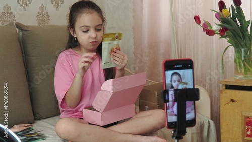 A beauty blogger, a girl dressed in a pink T-shirt, applies eye patches, films videos about her daily skincare routine, and reviews cosmetic products on social media. She films the videos on her phone