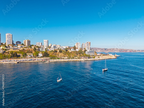 Aerial view of coastal Valparaiso city skyline with modern buildings, luxury apartments, and sailboats on the calm blue water of the Pacific Ocean in Chile