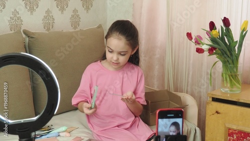 A beauty blogger, a girl dressed in a pink T-shirt, applies eye patches, films videos about her daily skincare routine, and reviews cosmetic products on social media. She films the videos on her phone