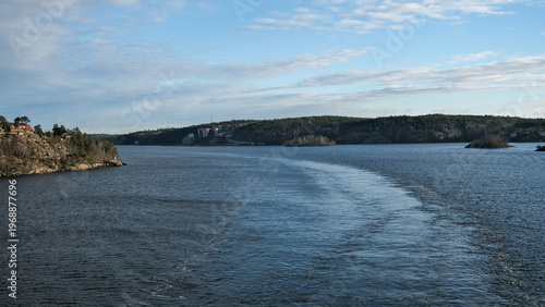 Scenic view of a coastal fjord with a ship wake on the water.