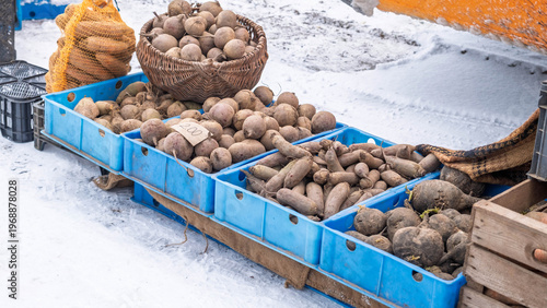 Beets and root vegetables at a snowy outdoor market.