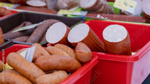 Smoked sausages and meat products in plastic bins at a market in Latvia.