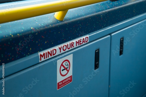 Obraz na płótnie Interior public transport sign reading “Mind Your Head” and “No Smoking” inside a bus in London, highlighting safety and passenger guidance in urban transit