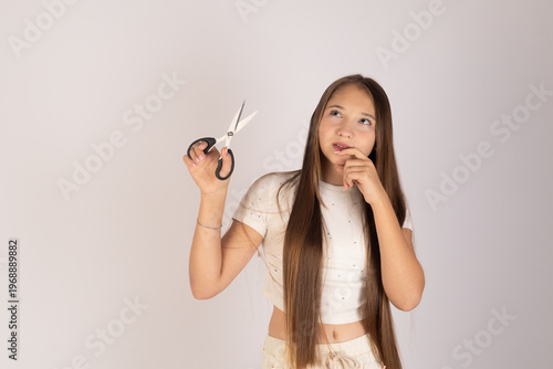 Girl holding scissors and looking confused