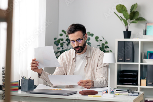 Billede på lærred Man in glasses reviewing business documents at home office
