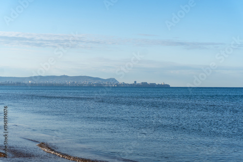 A panoramic view of the Black Sea and the resort town of Anapa, with calm blue waters under a clear summer sky. High-quality photo.
