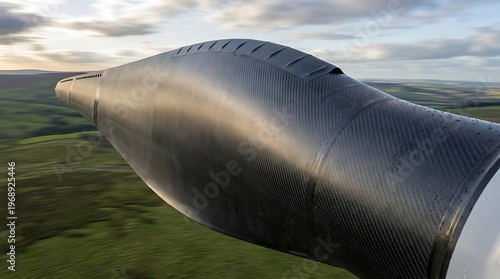 Close-up of wind turbine blade in green landscape at sunset