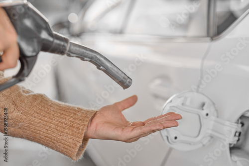 Fotografie Person checking a fuel pump nozzle with hand, expecting gasoline but no fuel flows