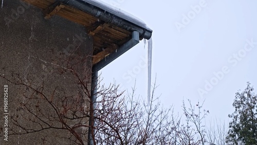 Massive Long Dangerous Icicle Hanging from Frozen Rain Gutter Posing Injury Hazard for Pedestrians